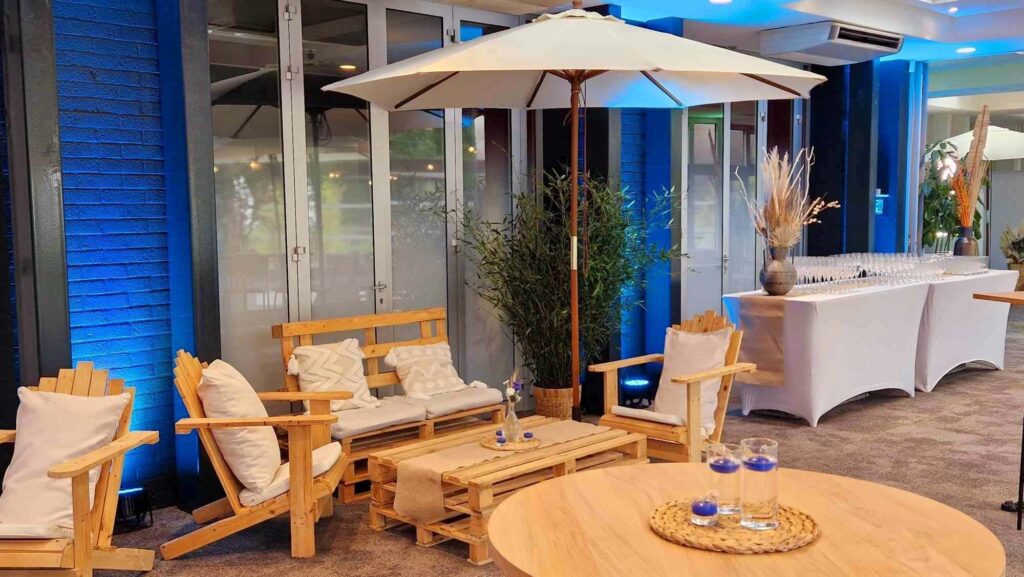 Décoration de mariage guinguette avec Nature Event. Bambou avec pot en osier, centre de table en verre fleuri avec des fleurs blanches et bleues sur un dessous d'assiette en osier et bougies bleues