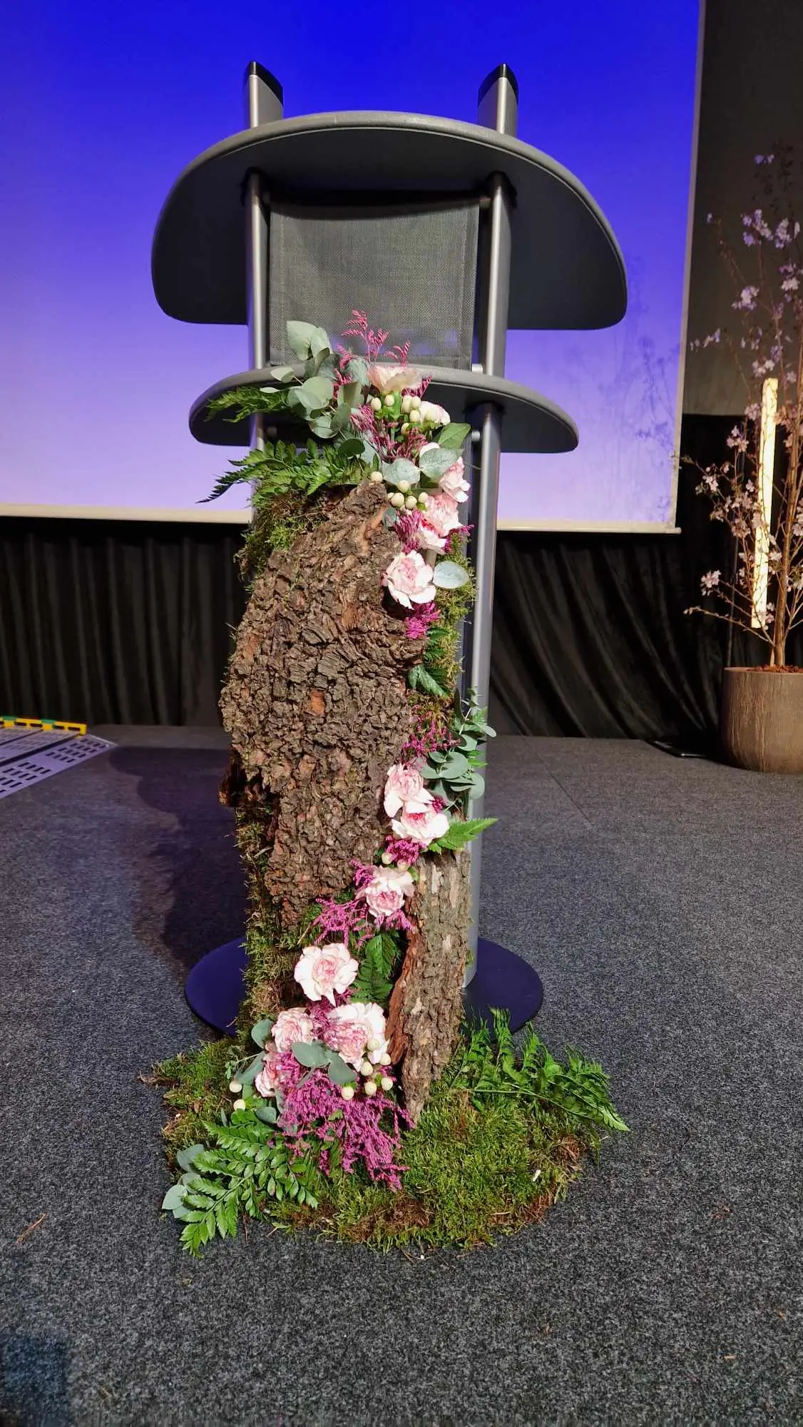 Décoration de pupitre sur scène avec des fleurs, écorces d'arbre, des éléments de décorations naturels pour une décoration florale lors d'une conférence